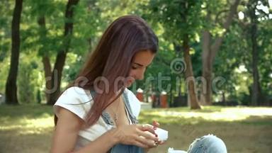 夏天，可爱的黑发女人<strong>坐在公园里</strong>，拿着一份小礼物